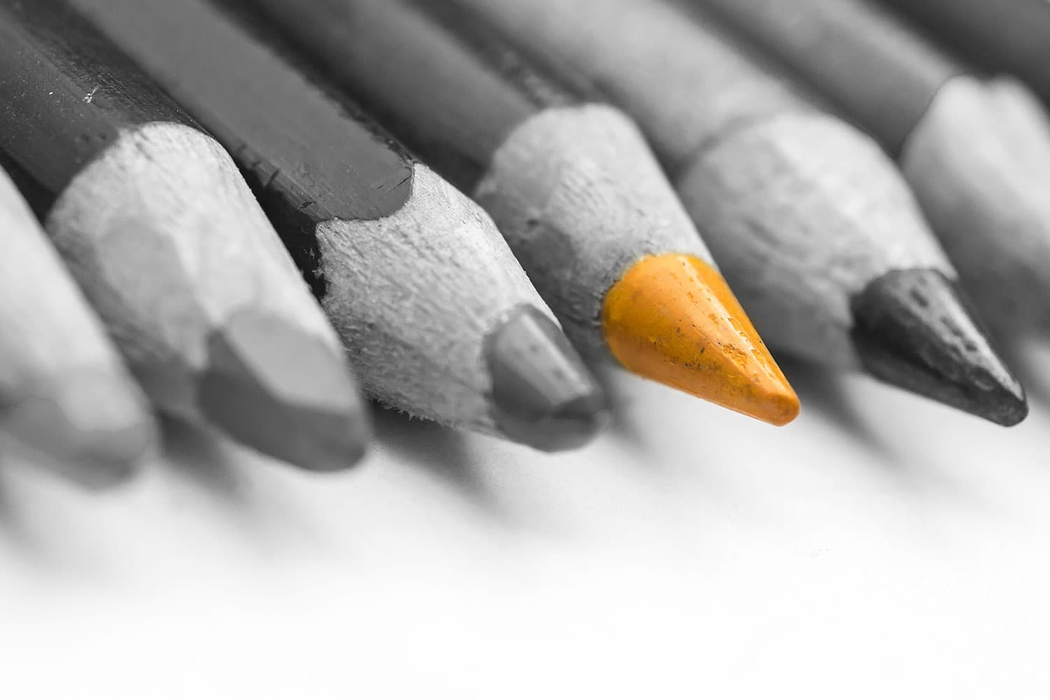A single gold pencil standing out among a row of grey pencils